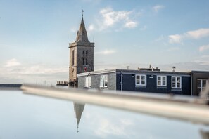 A tower with a clock, a building with windows, and a clear sky. - Kidston Court (No 9) (St Andrews)