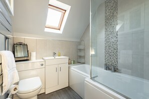 A modern bathroom with a skylight, a bathtub, and a toilet. - Kidston Court (No 9) (St Andrews)