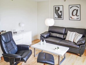 A modern living room with a leather sofa, a matching armchair, a white coffee table, and a small cabinet. - 4 Person Holiday Home in Thyboron (Thyborøn)