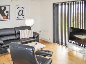 Un salon moderne avec un canapé en cuir, une table basse et un téléviseur à écran plat.