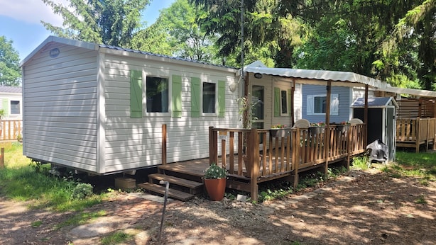 A mobile home with a porch, a small deck, and a garden area with potted plants. - MobileHome VERONA, air-conditioned, TV, WIFI, 15 min from Europa-Park! (Boofzheim)