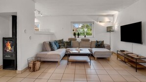 Una sala de estar moderna con un sofá modular, una chimenea, un televisor y una ventana con vista a zonas verdes.