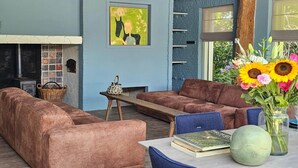 A cozy living room with a fireplace, a sofa set, and a bookshelf.