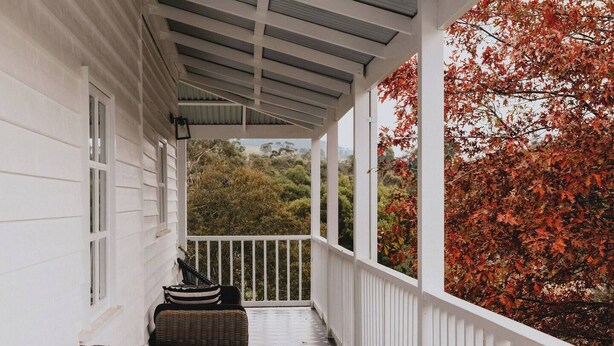 A covered porch with a checkered floor, white railings, and a view of autumn foliage. - The Notebook Haus in Omeo (Omeo)