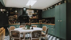 A kitchen with a round dining table, wicker chairs, a chandelier, and green cabinets. - The Notebook Haus in Omeo (Omeo)