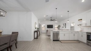 A modern kitchen with white cabinets, a dishwasher, and a dining area with a table and chairs.