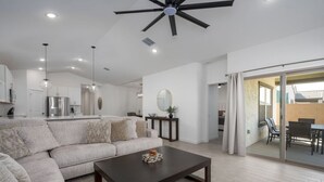 A modern living room with a sectional sofa, a dark coffee table, and a ceiling fan.