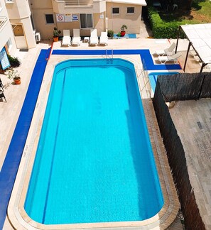A rectangular swimming pool with a blue interior and a surrounding deck area.