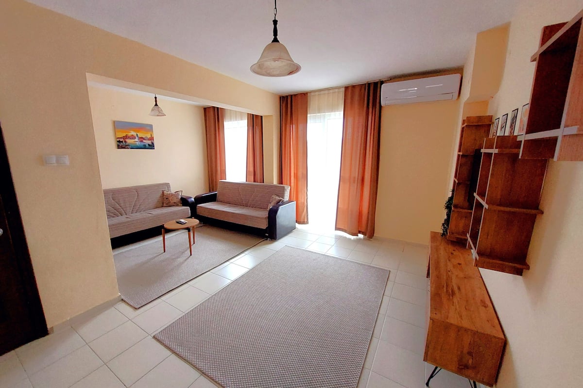 Een woonkamer met een bank, een salontafel, een vloerkleed en een houten kast.