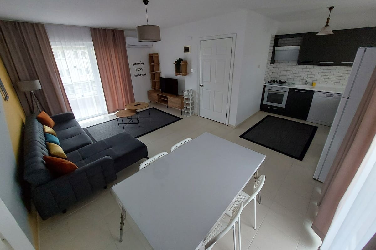 Een functionele woonruimte met een bank, eettafel, keukenhoek en televisie.
