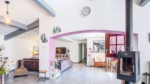 Un espacio habitable amplio con un techo alto, una chimenea y un reloj en la pared.