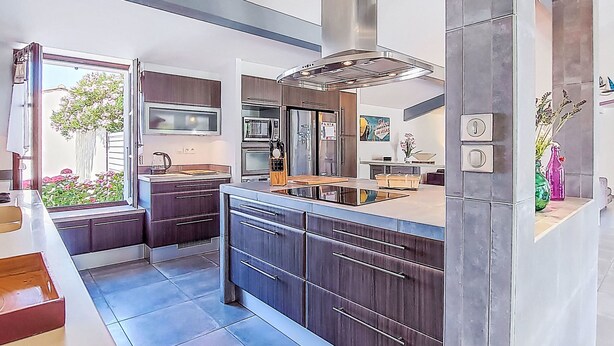 Una cocina moderna con armarios oscuros, electrodomésticos de acero inoxidable y una isla grande.