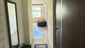 Un pasillo con una puerta de madera oscura, un banco, un espejo y un felpudo.