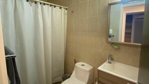 Un baño con inodoro, lavamanos y cortina de ducha.