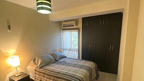 Un dormitorio con cama, mesita de noche, escritorio y armario.