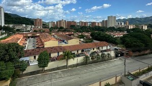 Un paisaje urbano con una combinación de edificios altos y bajos, cielo despejado y una zona de estacionamiento en primer plano.
