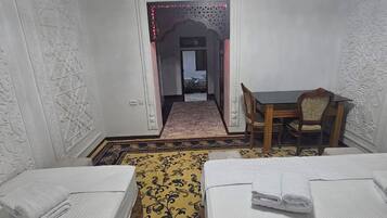 A hotel room with two beds, a dining table, and a chandelier.