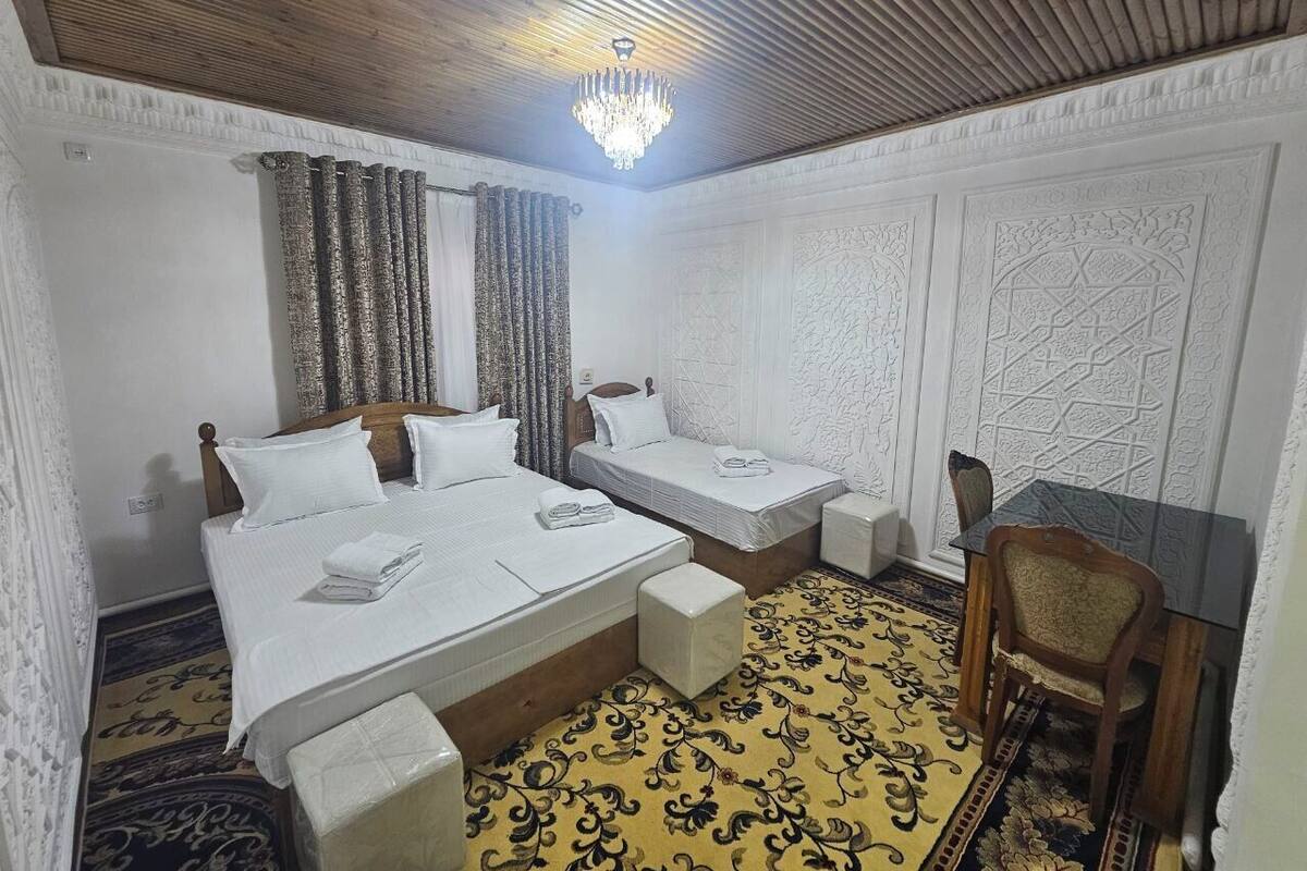 A hotel room with two beds, a desk, and a chair.
