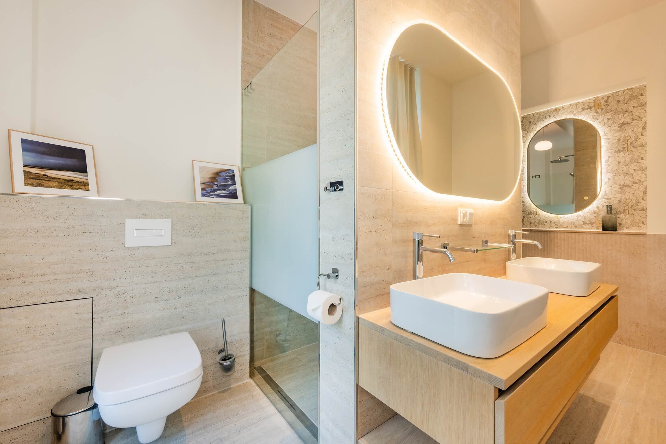 Un bagno moderno con il water, un box doccia in vetro e un mobile lavabo con due lavandini e uno specchio grande.