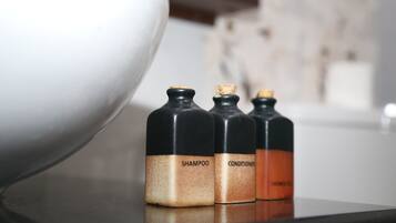 Drie flessen met de tekst 'shampoo' en 'conditioner' op een reflecterend oppervlak.