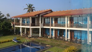 Un hôtel de deux étages doté d’une piscine, d’un espace extérieur aménagé et offrant une vue sur les palmiers.