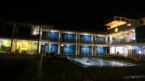 Un hôtel à plusieurs étages, doté d’une piscine extérieure et de balcons bien éclairés.