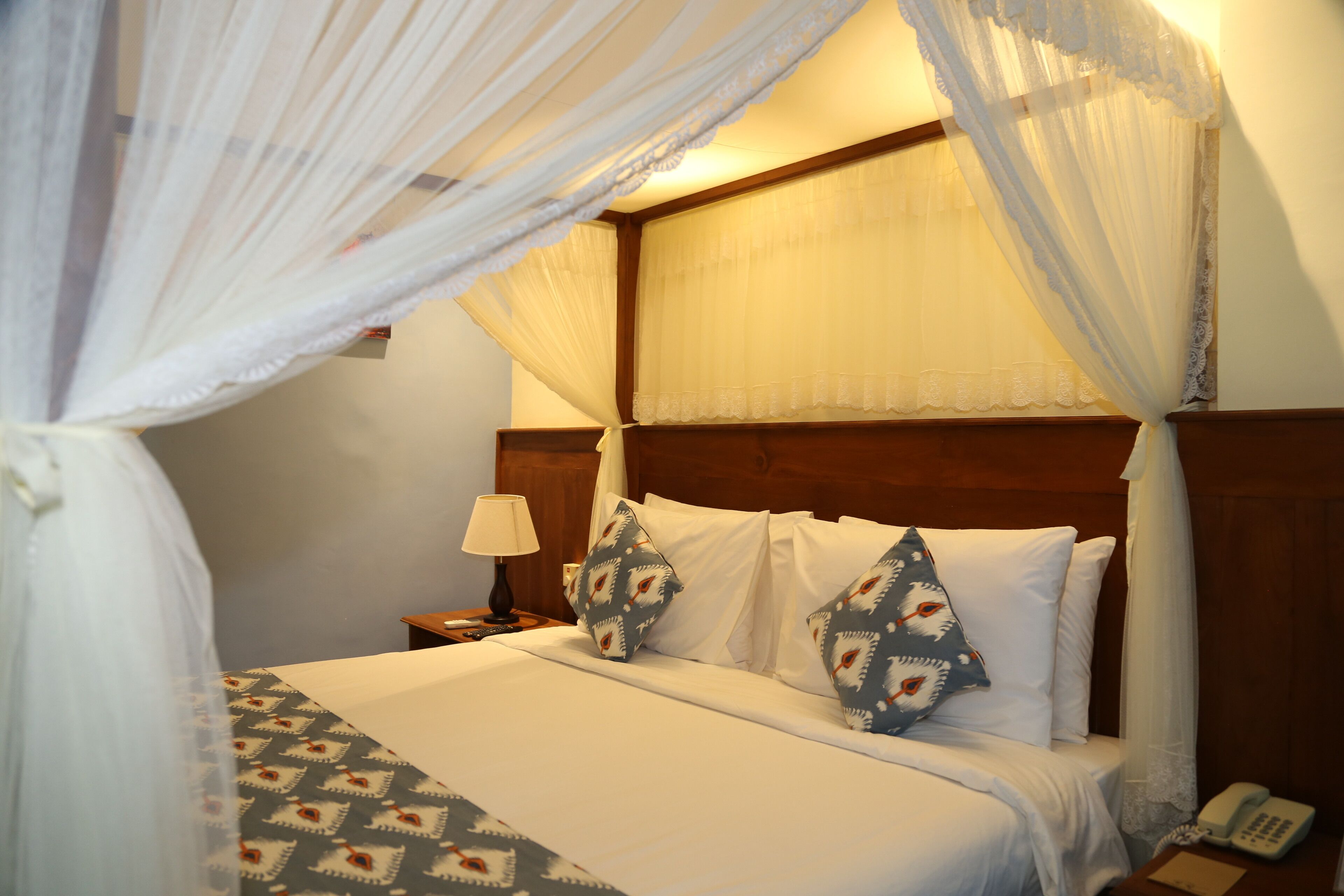 Une chambre d’hôtel avec un lit, une table de chevet, une lampe et un téléphone.