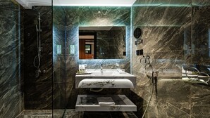 Ein modernes Badezimmer mit einer gläsernen Duschkabine, einem мраморной Waschbecken und einem großen Spiegel.