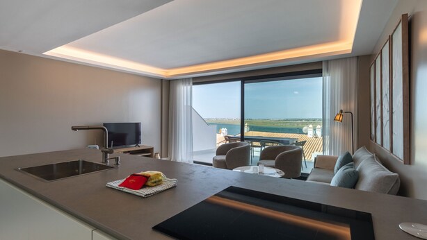 A modern kitchen with a built-in stove, a sink, and a dining area with a view of the cityscape.
