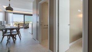 A modern hotel room with a balcony, a dining area with a round table and chairs, and a large window offering a view.