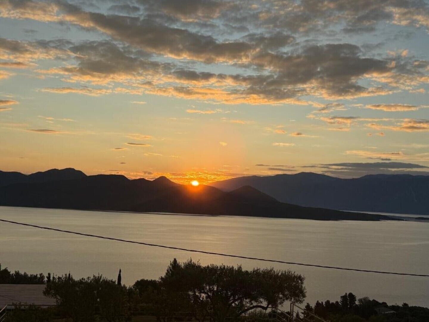 Un coucher de soleil sur un lac paisible, avec des montagnes en arrière-plan.