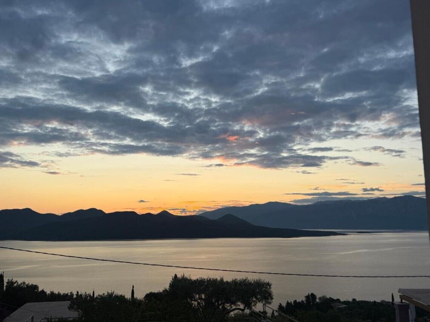 A view of a lake with mountains in the background and a cloudy sky.
