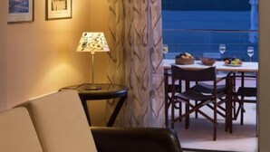 Una habitación acogedora con un sofá, una mesa con sillas, una lámpara y cuadros en la pared.