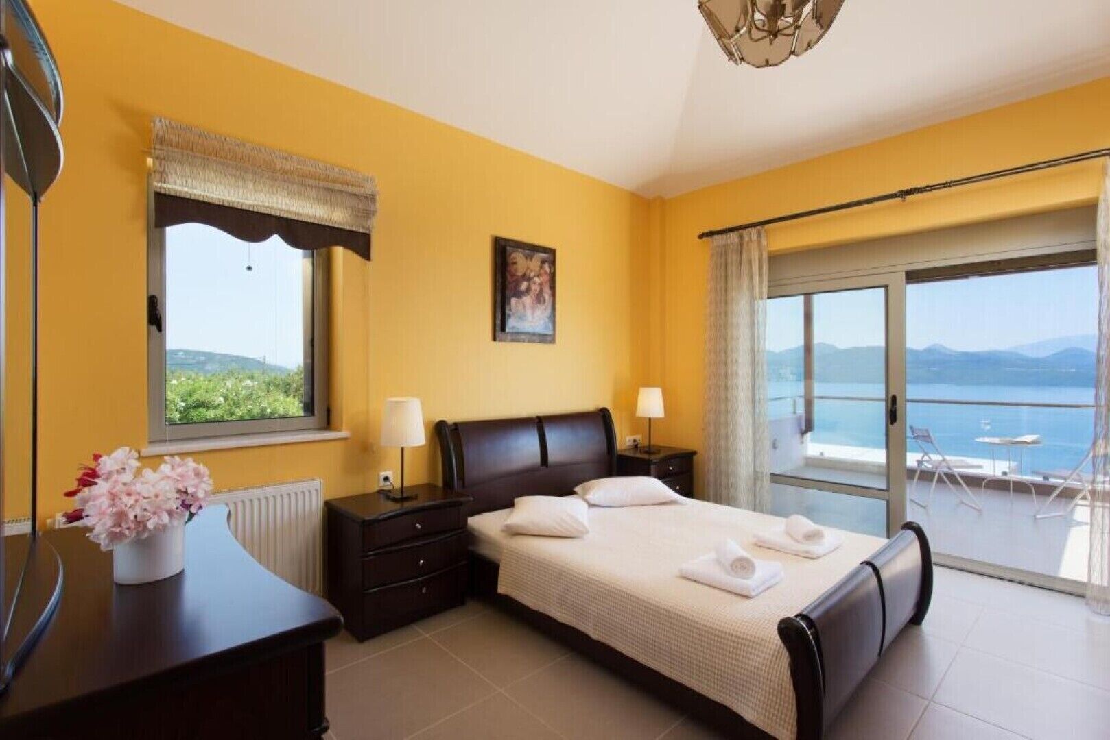 Quarto com cama, mesas de cabeceira, janela com vista, um quadro e varanda com vista.