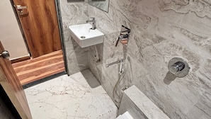 A bathroom with a wooden door, a white sink, a mirror, and a shower area. - Hotel Lavish Park (Mumbai)