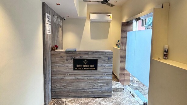 A reception area with a marble floor, a reception desk, a ceiling fan, and a wall-mounted air conditioning unit. - Hotel Lavish Park (Mumbai)