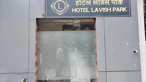 The entrance to Hotel Lavish Park with a clear signboard, a motorcycle parked outside, and a security camera on the wall. - Hotel Lavish Park (Mumbai)