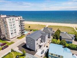 Zona residencial costera con un edificio grande, una casa más pequeña y una playa al fondo.