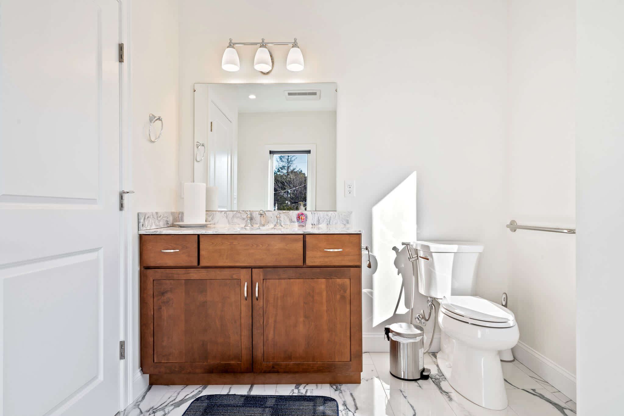 Une salle de bain moderne avec un meuble-lavabo en bois, des toilettes blanches et un sol en marbre.