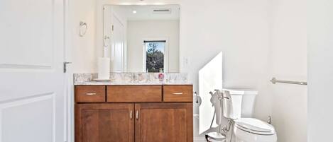Une salle de bain moderne avec un meuble-lavabo en bois, des toilettes blanches et un sol en marbre.