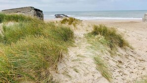 Egy homokdűnékkel és egy kőépítménnyel rendelkező strand.