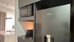 A modern kitchen with a stainless steel refrigerator, a microwave, and an easy access dispenser.