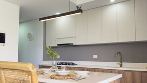 A modern kitchen with a central island, white cabinetry, and a stainless steel sink.