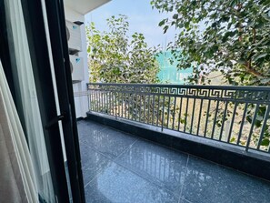 A balcony with a geometric railing, a tiled floor, and a view of trees and a fence. - Akshay Premium Suites (Gurugram)