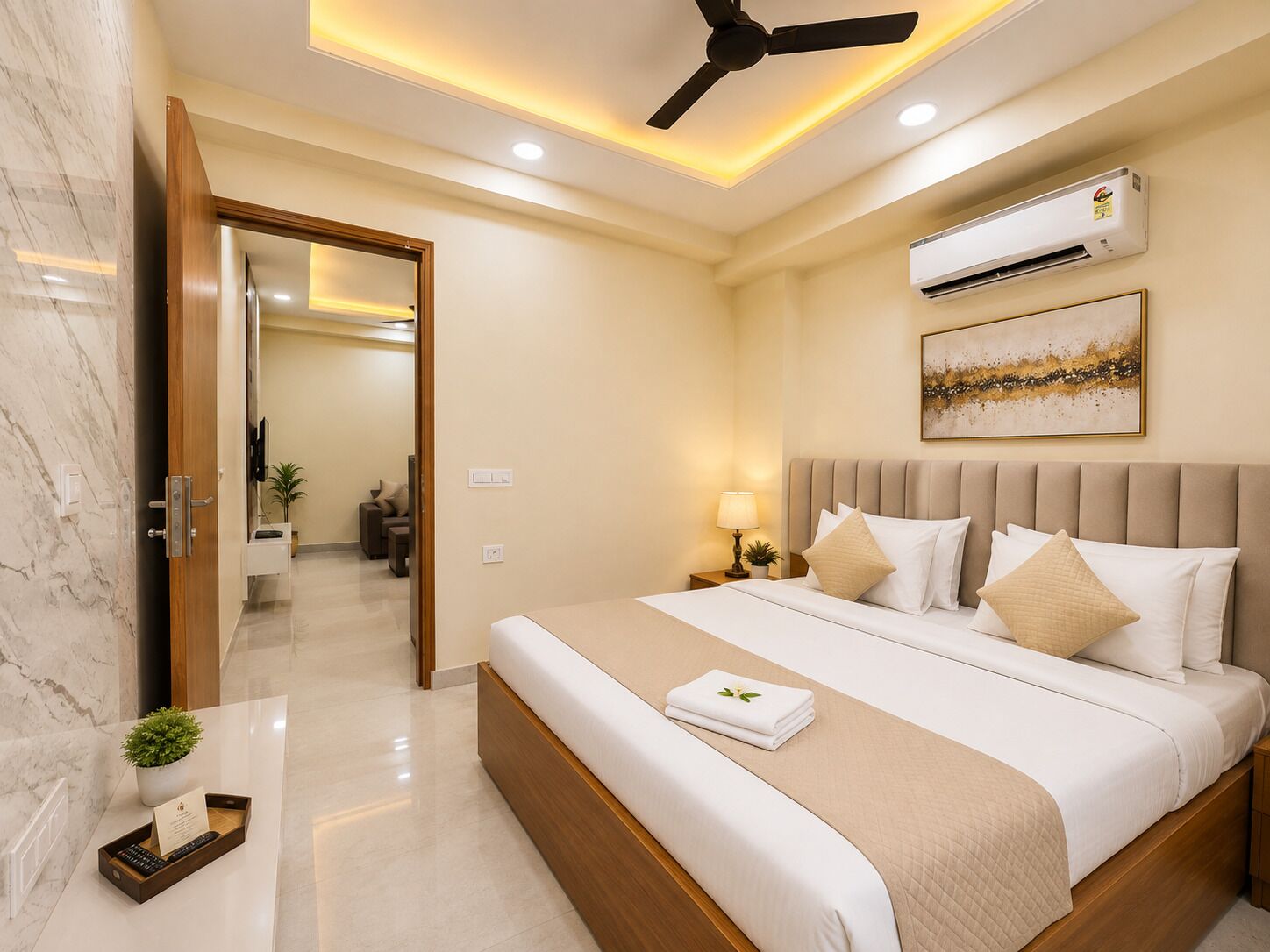 Una camera d'albergo con un letto, una ventola a soffitto, un condizionatore, un quadro e una piccola pianta sul comodino.
