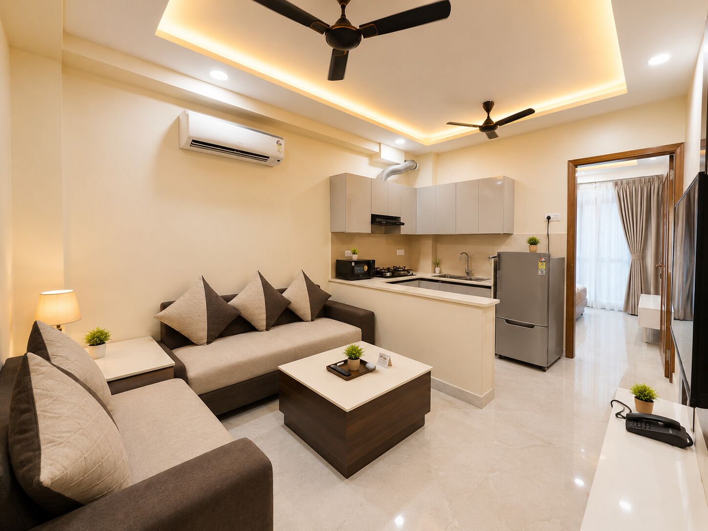 A modern living room with a sofa, coffee table, and a kitchen area with cabinets and appliances.