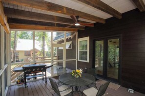 An outdoor patio with a round table, chairs, a grill, and a ceiling fan.