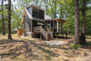 A cabin with a wooden exterior, a staircase, and a deck.