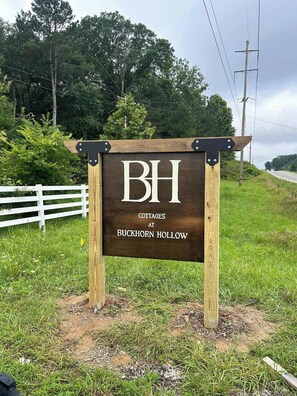 A wooden sign with "BH Cottages at Buckhorn Hollow" written on it.