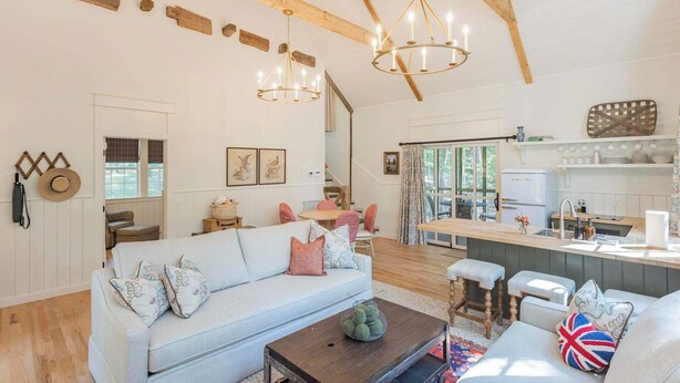 A spacious living area with a sofa, coffee table, and a kitchen in the background.